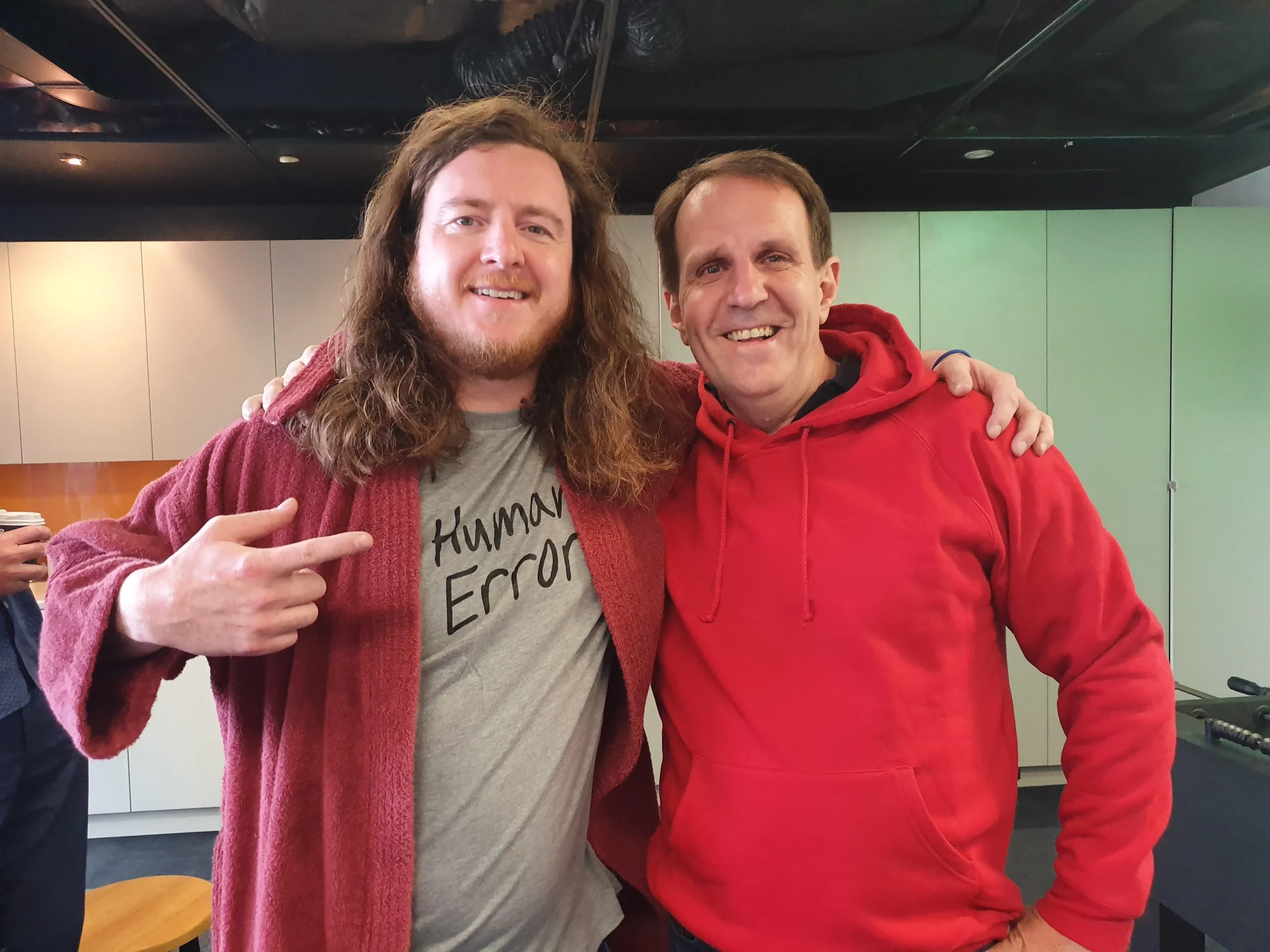 Colleagues joking about human error, one pointing to his "Human Error" slogan t-shirt